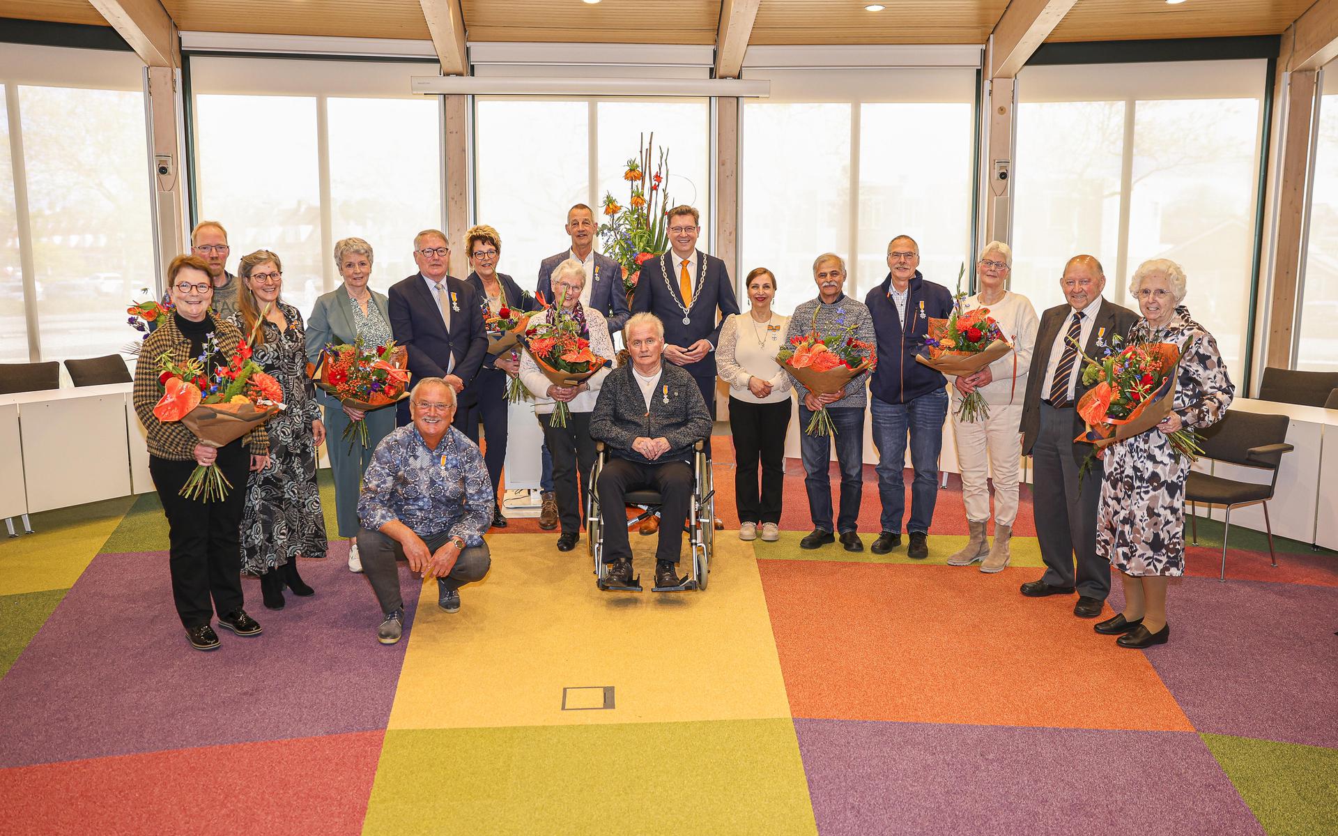 De acht gedecoreerden met hun partners en burgemeester Roger de Groot (met burgemeestersketting).