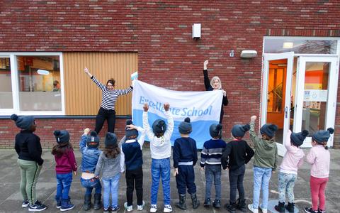 Ella van Essen en Sandra van der Tempel juichen met de kinderen nadat basisschool De Wissel in Luttelgeest voor de tweede keer het predicaat Excellente School heeft ontvangen.