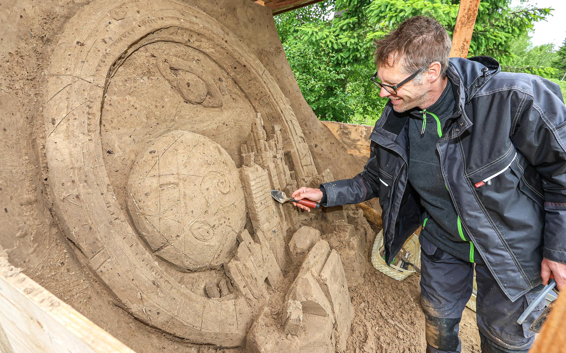 Kunstenaar Jeroen Advocaat legt de laatste hand aan de zandsculptuur ‘Stad van de toekomst’.