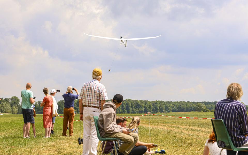 Bezoekers van de open dag van ZC NOP kijken hoe een toestel via een lier de lucht in wordt getrokken.