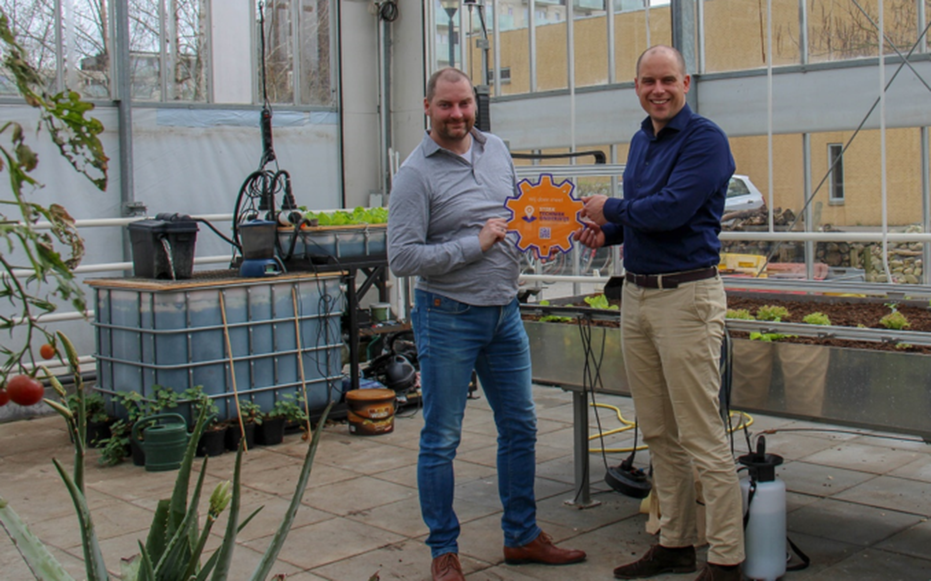 Michel Uytewaal (l) overhandigt het STO-embleem aan Matthijs van Gaalen van Aeres VMBO Emmeloord. Hij staat voor de Farmbot.